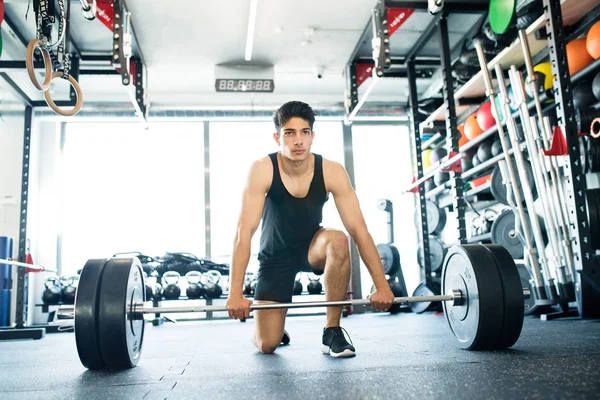 Молодой латиноамериканец в спортзале поднимает тяжелую штангу — стоковое фото