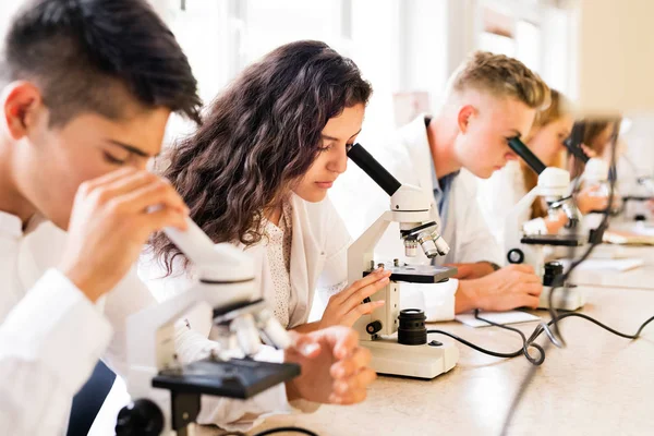 Красивые школьники с микроскопами в лаборатории . — стоковое фото