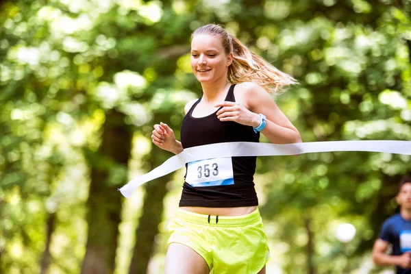 Jovem mulher correndo a corrida cruzando a linha de chegada . — Fotografia de Stock