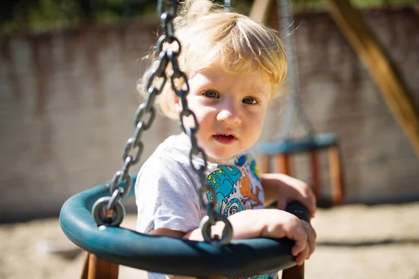 Niño en el columpio en el patio de recreo . —  Fotos de Stock
