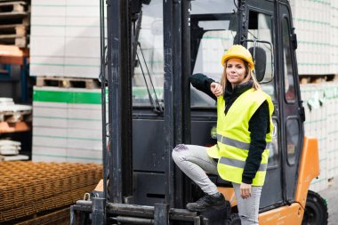 Kadın forklift kamyon şoförü bir endüstriyel alanda.