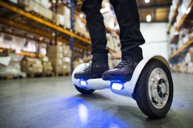 Erkek depo işçisi hoverboard üzerinde.