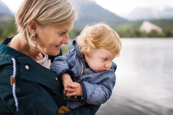 Senior vrouw met kleine jongen aan het meer. — Stockfoto