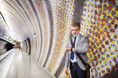 Bir metro istasyonunda bekleyen olgun iş adamı.