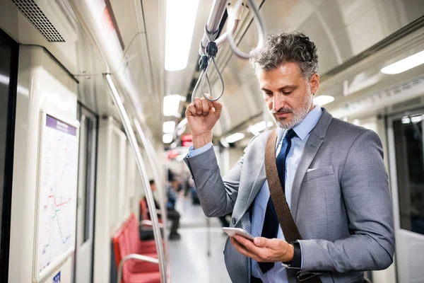 Uomo d'affari maturo con smartphone in un treno della metropolitana . — Foto Stock