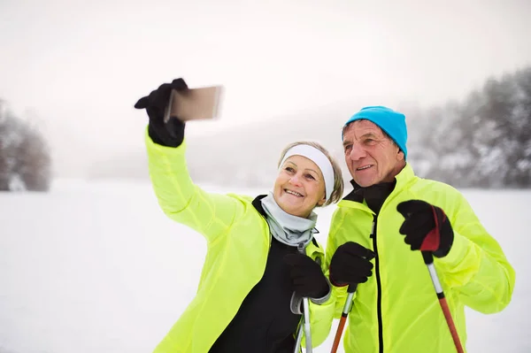 Senioren-Paar mit Smartphone beim Langlaufen. — Stockfoto