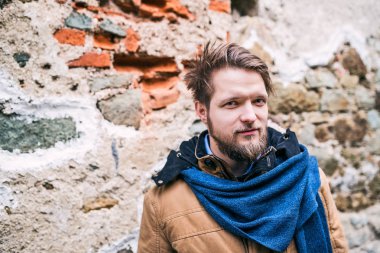 Bir genç hipster adam eski bir tuğla duvara karşı ayakta.