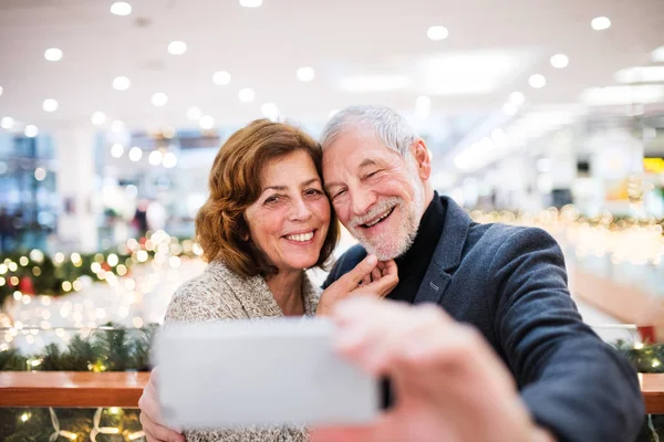 Starší pár s smartphone dělá vánoční nákupy. — Stock fotografie