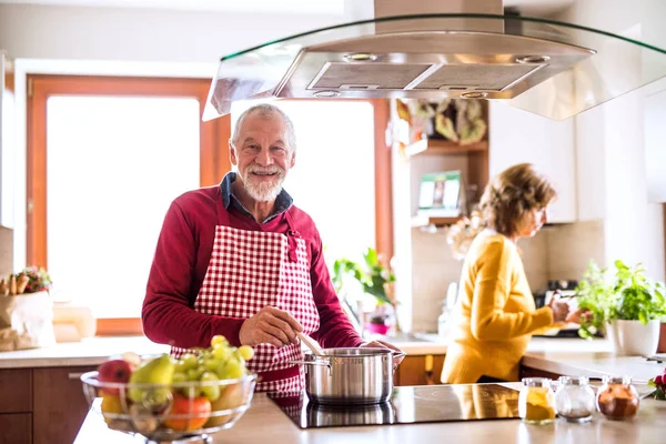 Casal sênior preparando comida na cozinha. — Fotografia de Stock