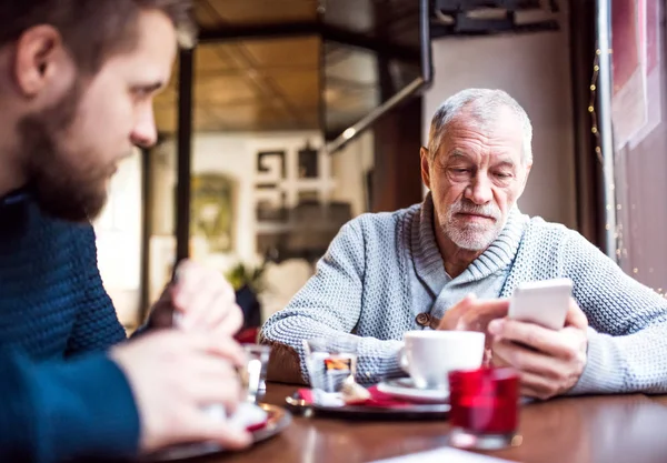 Senior vader met smartphone en jonge zoon in een café. — Stockfoto