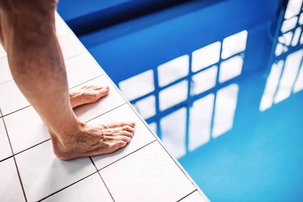 Pernas de um homem de pé na beira da piscina . — Fotografia de Stock