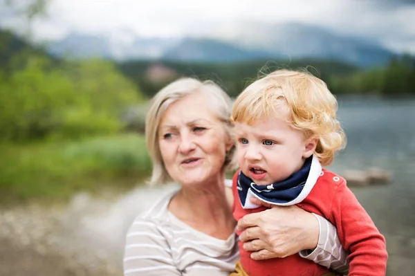 Старша жінка з маленьким хлопчиком біля озера, літній день . — стокове фото