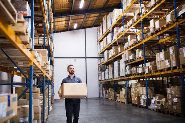 Male warehouse worker with a large box. — Stock Photo, Image