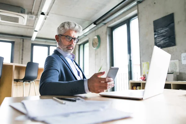 Mogen affärsman med laptop och smart phone. — Stockfoto