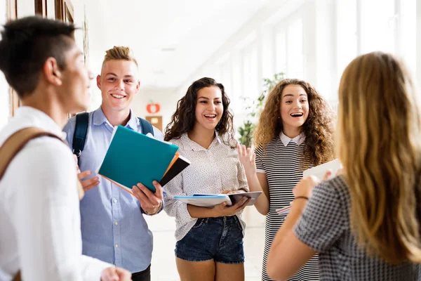 Tiener studenten lopen in high school hal, praten. — Stockfoto