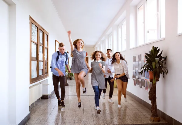 Adolescentes estudantes no salão do ensino médio saltando alto . — Fotografia de Stock