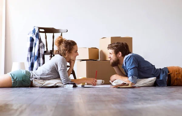 Young couple moving in new house, lying on the floor. — Stock Photo, Image