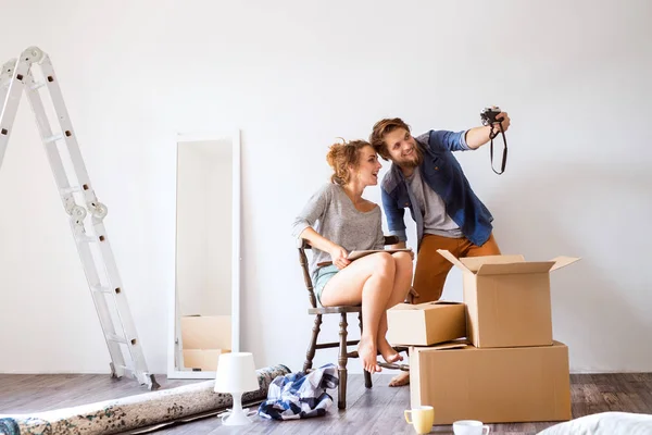Jeune couple déménageant dans une nouvelle maison, prenant des photos . — Photo