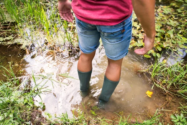 Tiener in rubber laarzen staande in lake. — Stockfoto