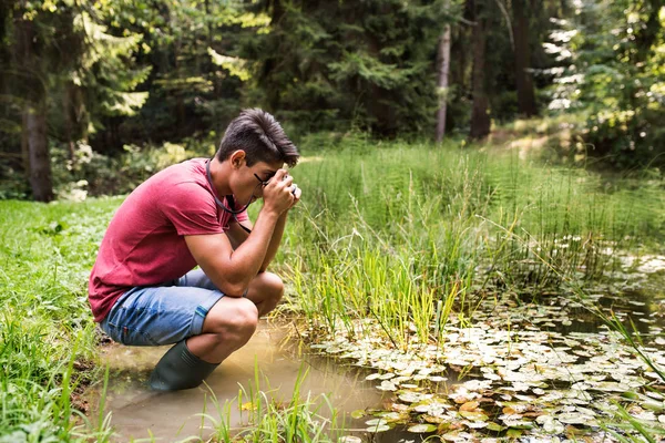Nastoletnim chłopcem z aparatu w jeziorze, biorąc obraz. — Zdjęcie stockowe