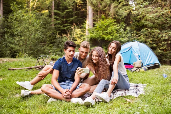 Adolescentes na frente da barraca acampar na floresta . — Fotografia de Stock