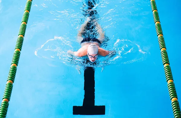 Senior man swimming in an indoor swimming pool. — Stock Photo, Image