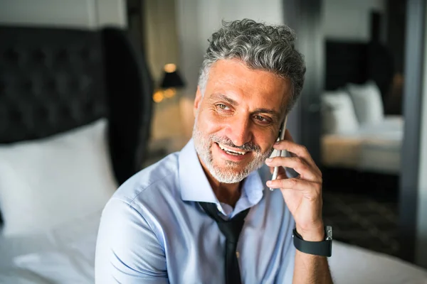 Mature businessman with smartphone in a hotel room. — Stock Photo, Image