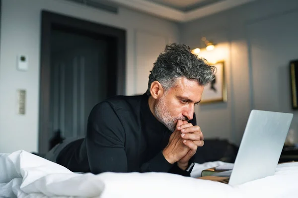 Uomo d'affari maturo con laptop in una camera d'albergo . — Foto Stock