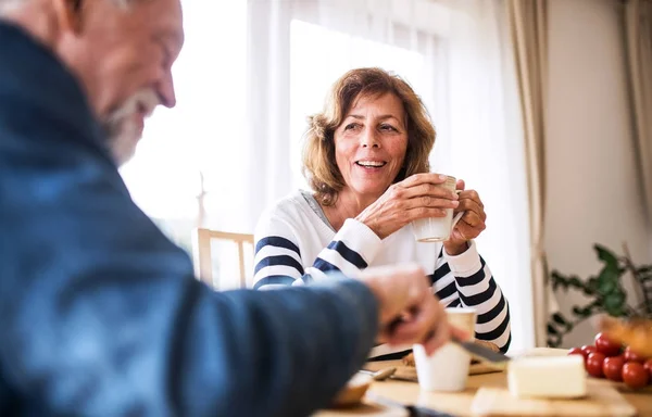 Senior couple eating breakfast at home.