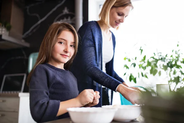 A small girl with her mother cooking at home. — Stock Photo, Image
