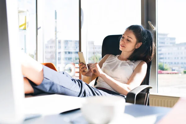 Empresária com um smartphone em seu escritório . — Fotografia de Stock