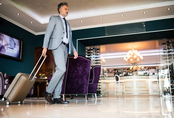 Mogen affärsman kommer in på hotellet med bagage. — Stockfoto