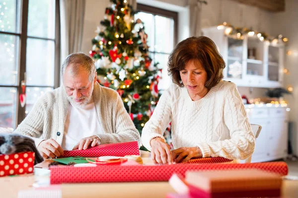 Senior para w swetry razem owijania prezenty świąteczne. — Zdjęcie stockowe