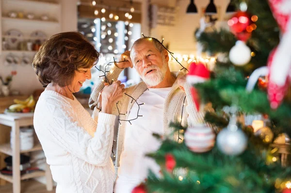 Senior couple at home decorating Christmas tree. — Stock Photo, Image