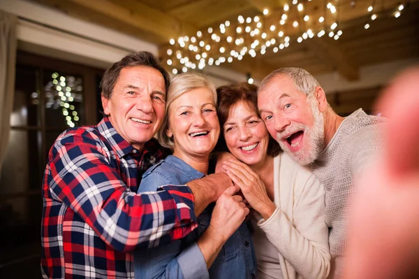 Senior vänner med smartphone tar selfie i juletid. — Stockfoto