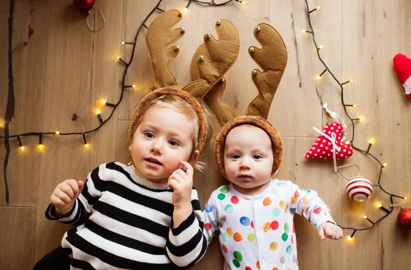 Kleine jongen en meisje op de vloer bij Kerstmis. — Stockfoto