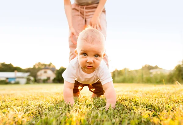 Baby boy with unrecognizable mother crawling outside. — Stock Photo, Image