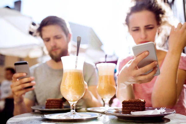 Молода пара зі смартфонами сидить у кафе . — стокове фото