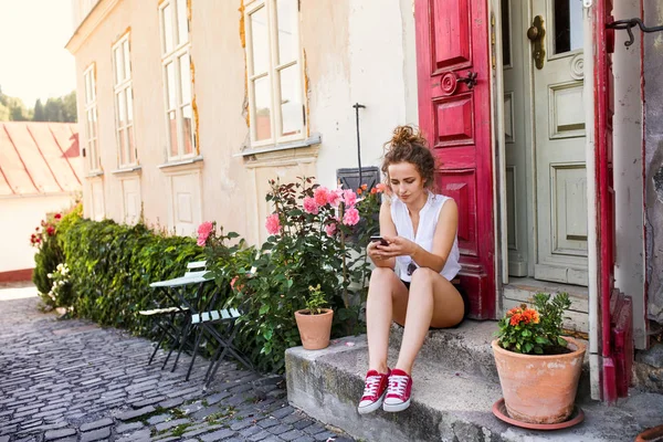 Jonge vrouw met een smartphone op de deur. — Stockfoto