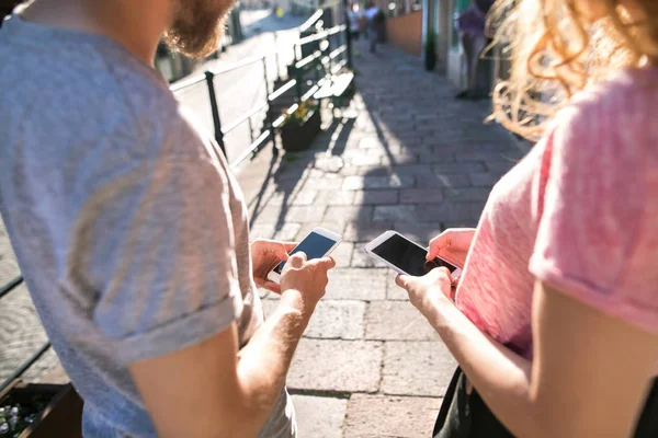 Couple de célibataires méconnaissables avec smartphones dans la rue . — Photo