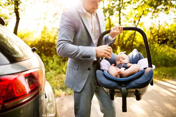 Hombre irreconocible llevando a su niña en un asiento de auto . — Foto de Stock