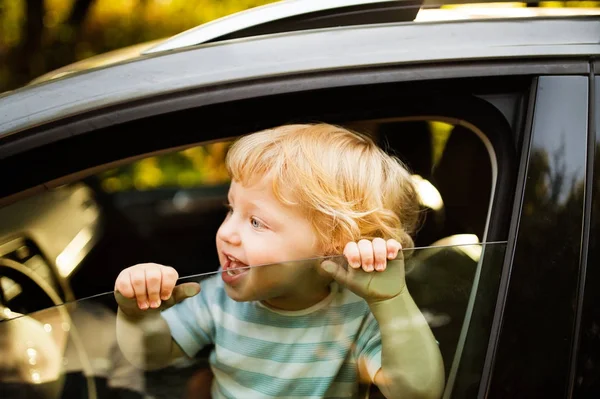 Petit garçon dans la voiture, regardant par la fenêtre, saluant . — Photo
