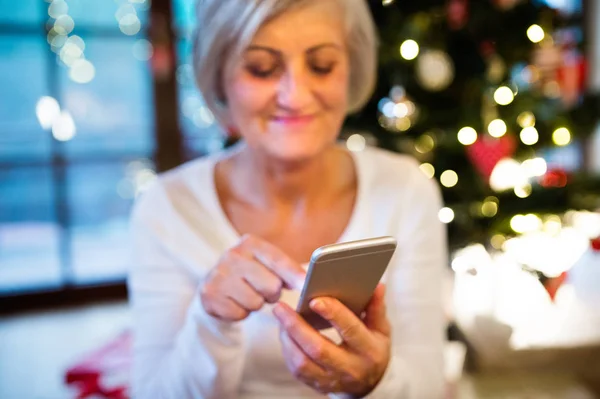 Senior woman with smartphone at Christmas time. — Stock Photo, Image