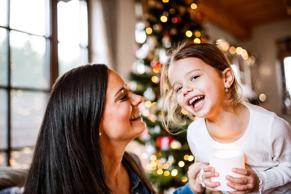 Jonge moeder met dochter bij de kerstboom samen. — Stockfoto