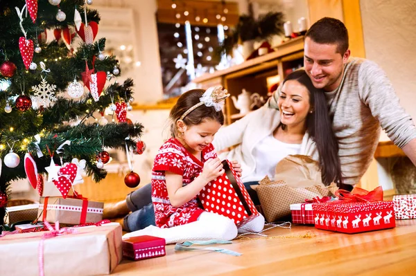 Família jovem com filha na árvore de Natal em casa . — Fotografia de Stock