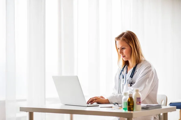 Médecin femme avec ordinateur portable travaillant au bureau . — Photo