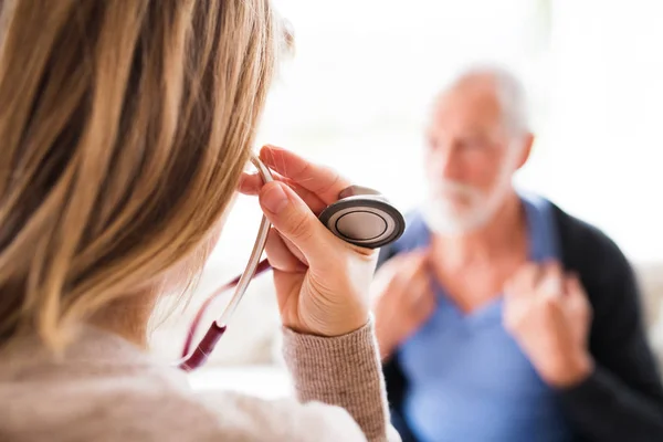 Visitante de salud y un hombre mayor durante la visita domiciliaria . — Foto de Stock