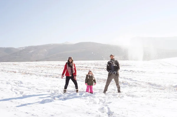 Pai e mãe com sua filha, brincando na neve . — Fotografia de Stock