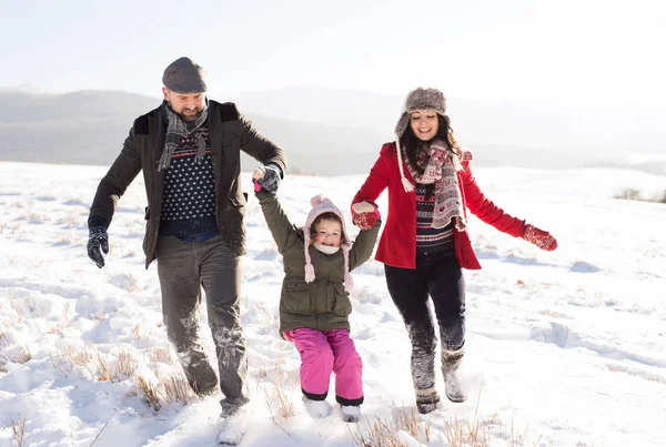 Vater und Mutter mit ihrer Tochter beim Spielen im Schnee. — Stockfoto