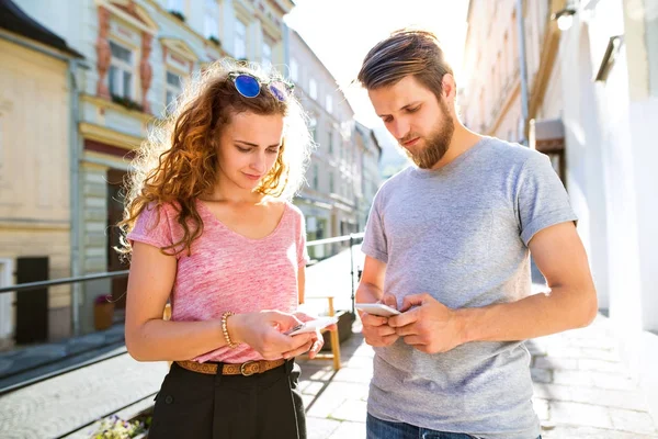 Unga par med smartphones på gatan. — Stockfoto